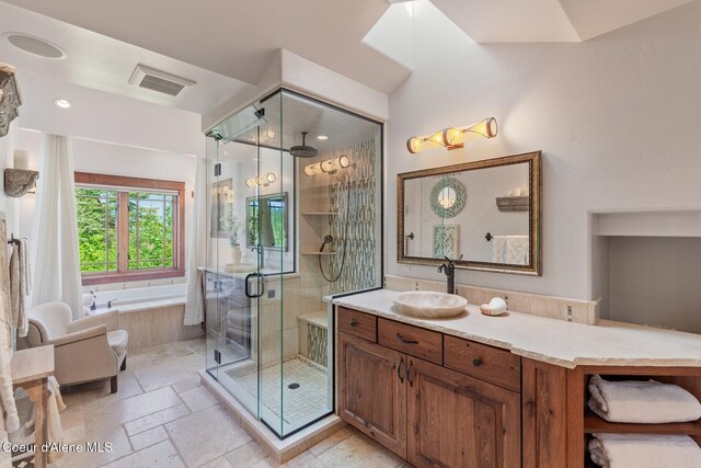 bathroom with a shower stall, a bath, vanity, and stone tile flooring