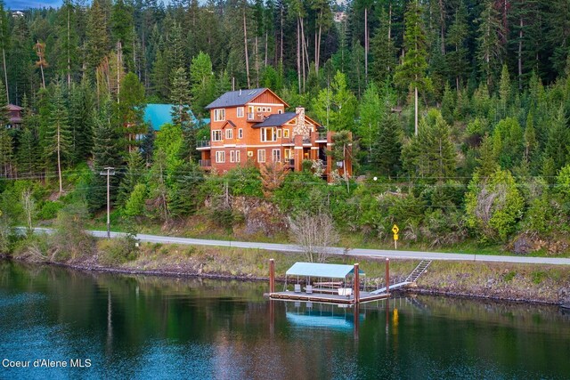 back of property featuring a forest view and a water view