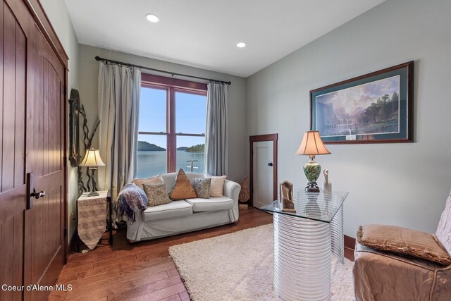 living area with wood finished floors, recessed lighting, a water view, and baseboards