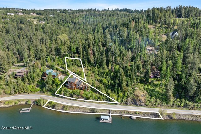view of property location featuring property boundaries highlighted, a heavily wooded area, and a large body of water