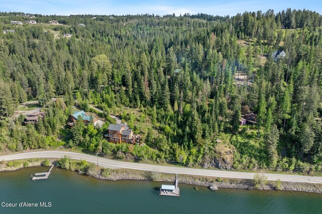 view of property location with a forest and a nearby body of water