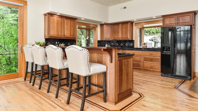 3361 Bottle Bay Rd, Sagle, ID 83860 - kitchen featuring black fridge, light wood-style flooring, brown cabinetry, and dark countertops
