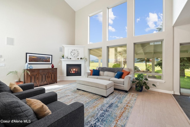 22385 N Ranch View Dr, Rathdrum, ID 83858 - living area with high vaulted ceiling, a lit fireplace, baseboards, and wood finished floors