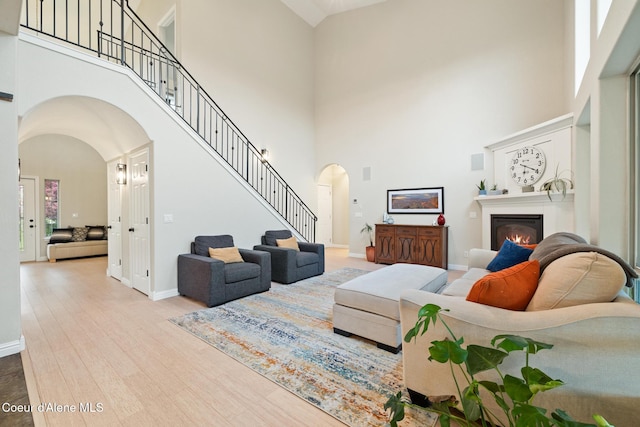 22385 N Ranch View Dr, Rathdrum, ID 83858 - living area featuring arched walkways, a towering ceiling, stairway, a glass covered fireplace, and wood finished floors