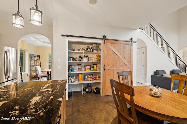 22385 N Ranch View Dr, Rathdrum, ID 83858 - dining space with arched walkways, a barn door, dark tile patterned flooring, and stairs