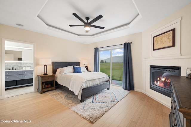 22385 N Ranch View Dr, Rathdrum, ID 83858 - bedroom featuring a raised ceiling, access to exterior, a fireplace, light wood-type flooring, and ensuite bathroom