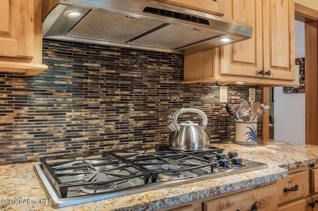 521 Shady Pines Loop, Priest Lake, ID 83856 - kitchen featuring wall chimney range hood, stainless steel gas stovetop, backsplash, and light brown cabinetry
