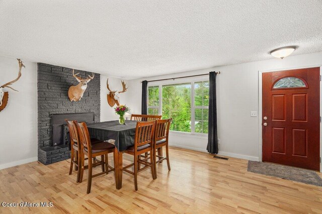 204 Sunrise Dr, Pinehurst, ID 83850 - dining area with a textured ceiling, light wood-type flooring, baseboards, and a stone fireplace