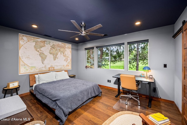 11679 N Avondale Loop, Hayden, ID 83835 - bedroom featuring a barn door, baseboards, recessed lighting, wood finished floors, and a desk