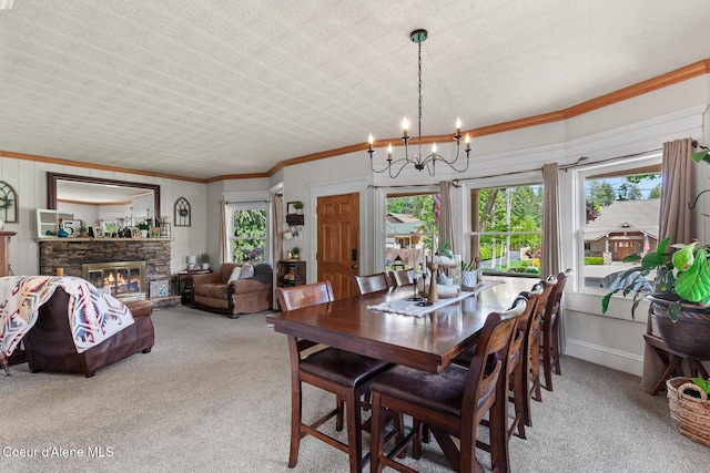 dining room with light colored carpet, a chandelier, ornamental molding, and a stone fireplace