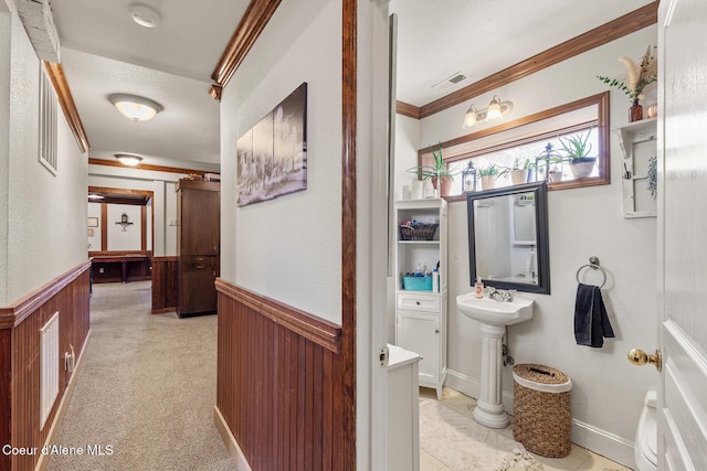 corridor featuring wainscoting, ornamental molding, wooden walls, and a textured ceiling