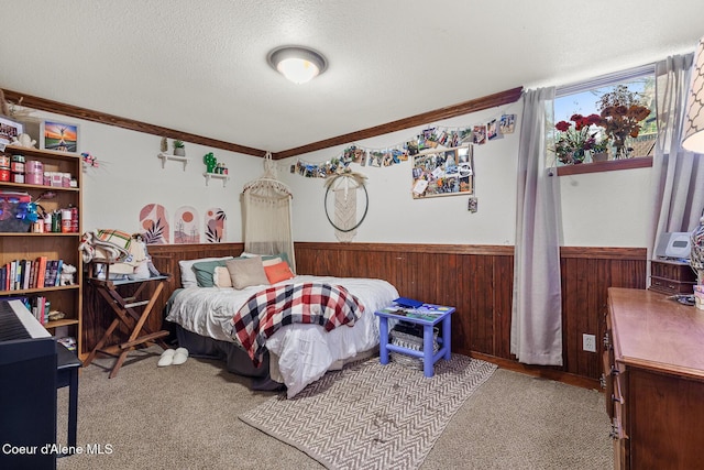 bedroom with a textured ceiling, wainscoting, wooden walls, crown molding, and carpet
