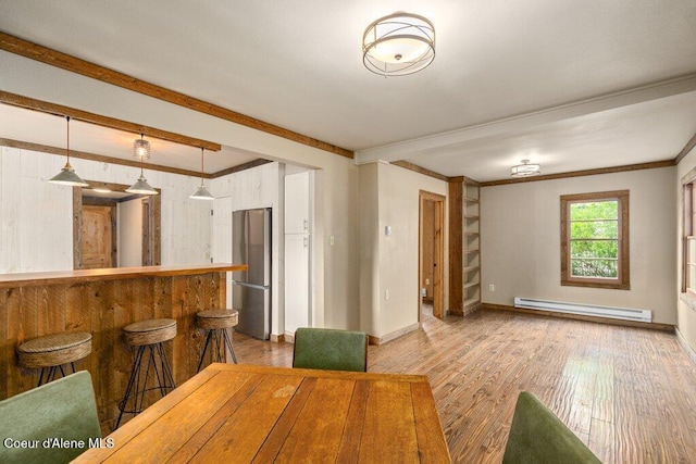 707 Washington Ave, Sandpoint, ID 83864 - dining space with a baseboard heating unit, light wood-style flooring, baseboards, and crown molding