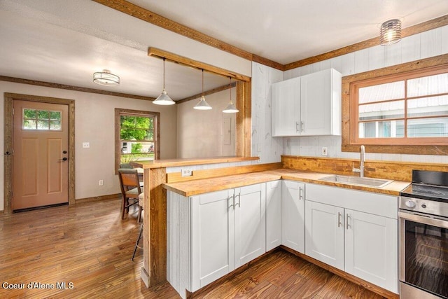 707 Washington Ave, Sandpoint, ID 83864 - kitchen with stainless steel range with electric stovetop, a sink, a peninsula, ornamental molding, and white cabinets