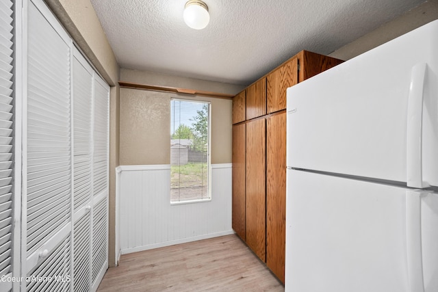 1706 E Thomas Ln, Coeur Dalene, ID 83815 - kitchen with freestanding refrigerator, wainscoting, a textured ceiling, light wood-type flooring, and brown cabinetry