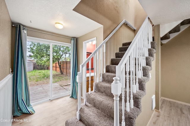 1706 E Thomas Ln, Coeur Dalene, ID 83815 - staircase featuring wood finished floors, a textured ceiling, a textured wall, and baseboards
