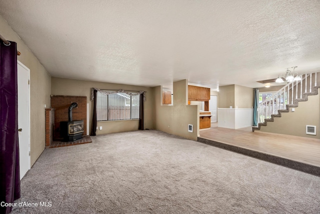 1706 E Thomas Ln, Coeur Dalene, ID 83815 - unfurnished living room with a textured ceiling, a wood stove, carpet floors, and stairs