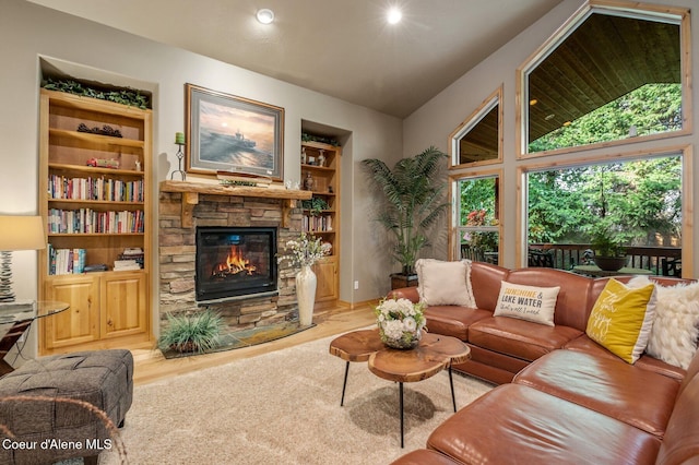 living area with a stone fireplace, vaulted ceiling, built in shelves, wood finished floors, and recessed lighting