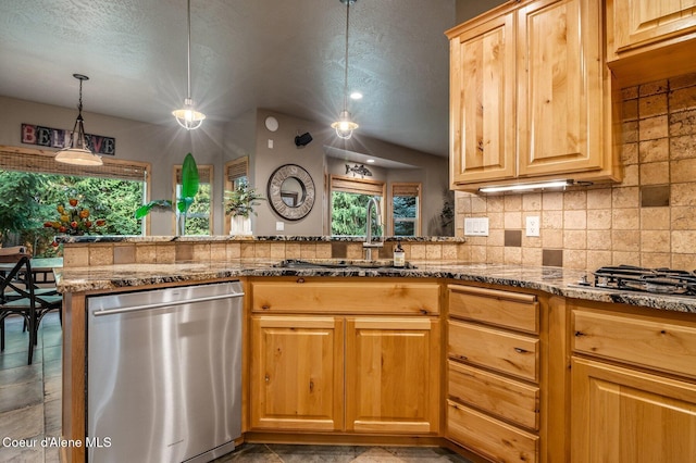 kitchen featuring appliances with stainless steel finishes, a sink, stone counters, pendant lighting, and lofted ceiling