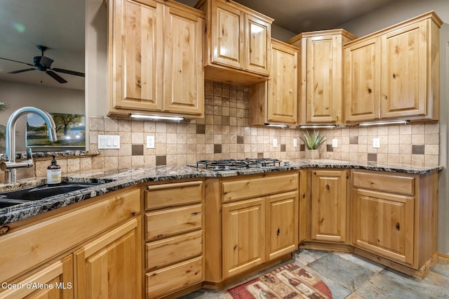 kitchen featuring a sink, ceiling fan, stainless steel gas stovetop, and backsplash