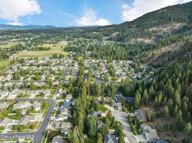 aerial overview of property's location featuring mountains, a forest, and nearby suburban area