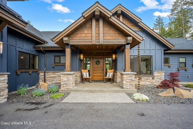 1230 E Amulet Cir, Rathdrum, ID 83858 - view of front of house with stone siding, board and batten siding, a shingled roof, and covered porch