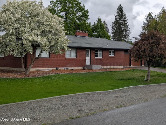 ranch-style house featuring brick siding, a front lawn, driveway, and a chimney