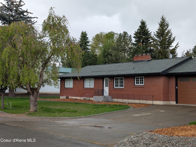 single story home with concrete driveway, brick siding, a front lawn, and an attached garage