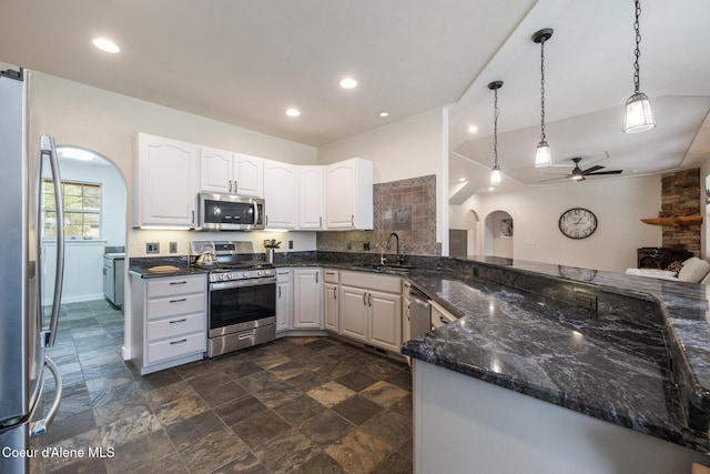 27464 N Timber Ridge Rd, Rathdrum, ID 83858 - kitchen with appliances with stainless steel finishes, a sink, a ceiling fan, dark stone finish flooring, and dark stone counters