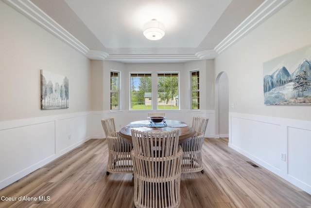 27464 N Timber Ridge Rd, Rathdrum, ID 83858 - dining space with arched walkways, wood finished floors, a tray ceiling, a wainscoted wall, and a decorative wall
