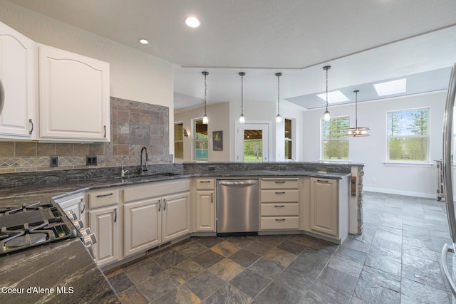 27464 N Timber Ridge Rd, Rathdrum, ID 83858 - kitchen with dishwasher, a sink, stone tile floors, a skylight, and backsplash