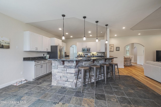 27464 N Timber Ridge Rd, Rathdrum, ID 83858 - kitchen featuring stainless steel appliances, arched walkways, a breakfast bar, baseboards, and recessed lighting