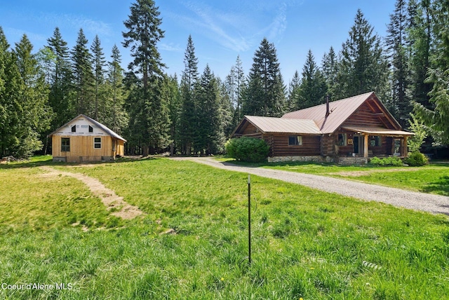 view of front facade featuring a front lawn, metal roof, a wooded view, and log siding