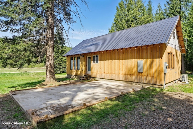chalet / cabin featuring metal roof, a front lawn, and ac unit