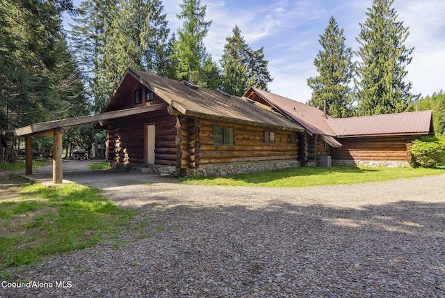 view of front of house featuring gravel driveway, log siding, and a carport
