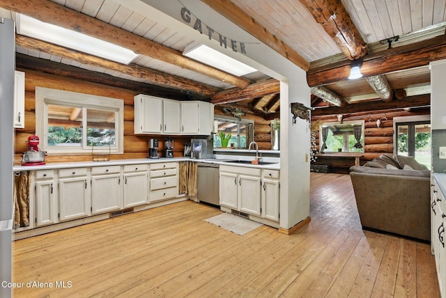 kitchen with dishwasher, a sink, healthy amount of natural light, rustic walls, and light wood-style floors