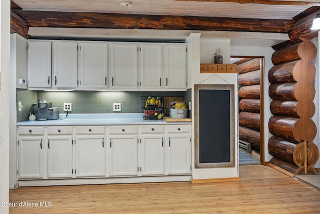kitchen featuring beamed ceiling, backsplash, light countertops, white cabinetry, and light wood finished floors