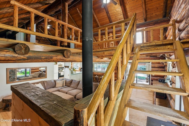 stairway with wooden ceiling, hardwood / wood-style floors, high vaulted ceiling, and beam ceiling