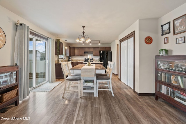 6595 W Covenant St, Rathdrum, ID 83858 - dining area with wood finished floors, a chandelier, rail lighting, and baseboards