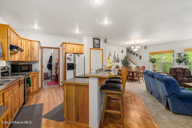 911 French Gulch Rd, Kingston, ID 83839 - kitchen featuring white fridge with ice dispenser, electric stove, under cabinet range hood, black microwave, and open floor plan