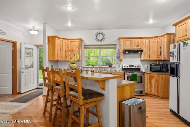 911 French Gulch Rd, Kingston, ID 83839 - kitchen with white fridge with ice dispenser, electric stove, under cabinet range hood, black microwave, and a breakfast bar
