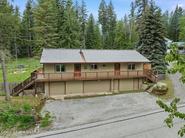 1072 Upland Dr, Sandpoint, ID 83864 - view of front of house featuring stairway, driveway, metal roof, and a view of trees