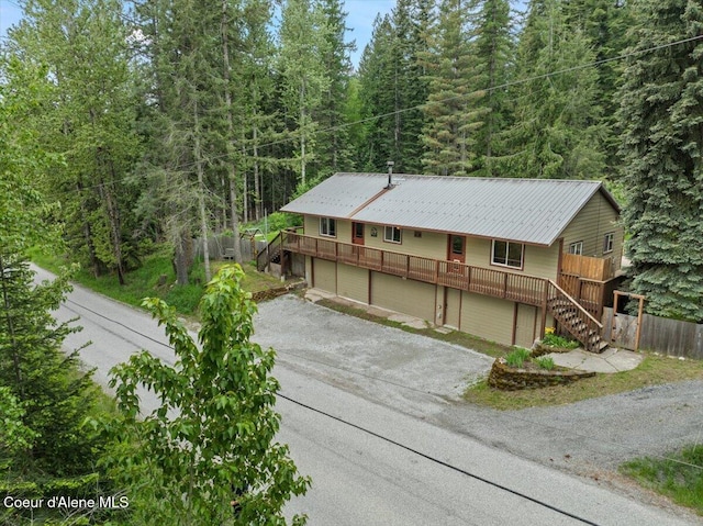 1072 Upland Dr, Sandpoint, ID 83864 - ranch-style home with stairs, gravel driveway, metal roof, and a forest view