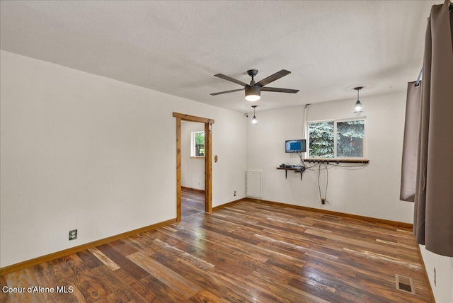 1072 Upland Dr, Sandpoint, ID 83864 - unfurnished living room featuring wood finished floors, baseboards, a ceiling fan, plenty of natural light, and a textured ceiling