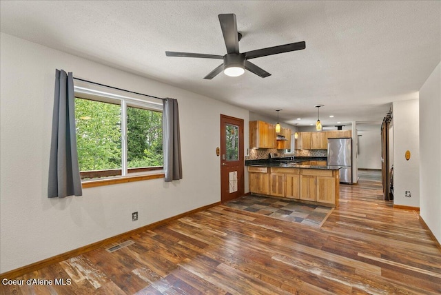 1072 Upland Dr, Sandpoint, ID 83864 - kitchen with freestanding refrigerator, dark countertops, dark wood finished floors, baseboards, and a textured ceiling