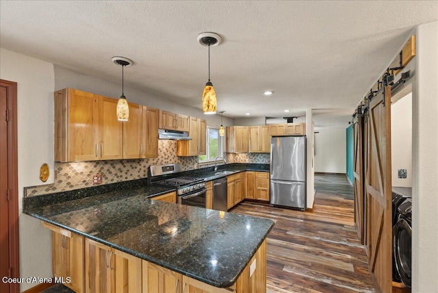 1072 Upland Dr, Sandpoint, ID 83864 - kitchen featuring stainless steel appliances, under cabinet range hood, a sink, a peninsula, and dark wood-style floors