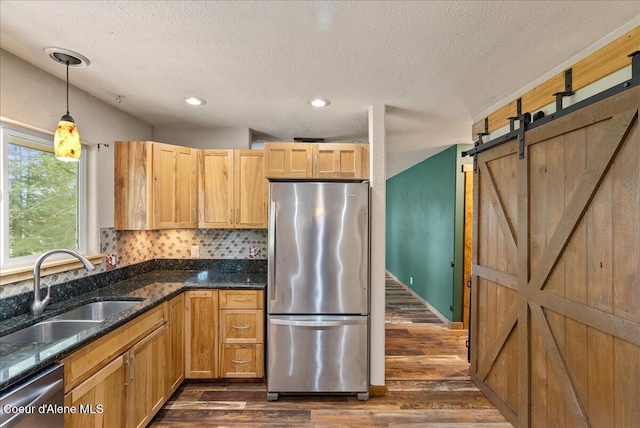 1072 Upland Dr, Sandpoint, ID 83864 - kitchen with appliances with stainless steel finishes, a sink, dark wood-style floors, a barn door, and a textured ceiling