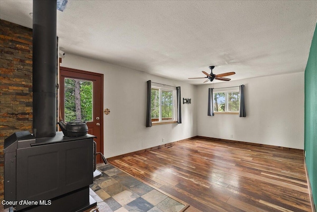 1072 Upland Dr, Sandpoint, ID 83864 - unfurnished office with a wood stove, healthy amount of natural light, a textured ceiling, a ceiling fan, and wood-type flooring
