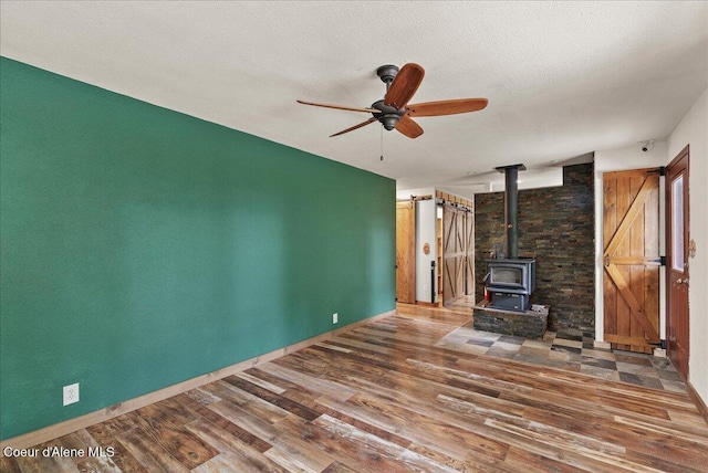 1072 Upland Dr, Sandpoint, ID 83864 - unfurnished living room featuring wood finished floors, a wood stove, a ceiling fan, and baseboards