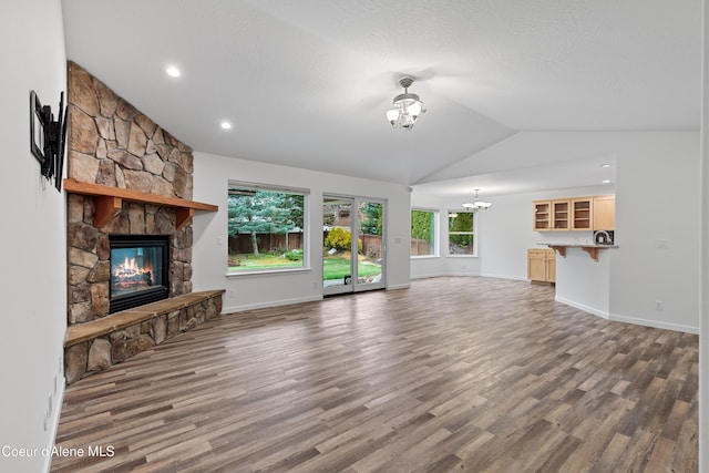 5519 N Wade St, Coeur Dalene, ID 83815 - unfurnished living room with a chandelier, lofted ceiling, a stone fireplace, wood finished floors, and baseboards